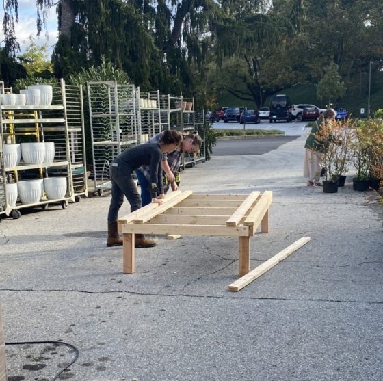 Two people working on a wood display outdoors.
